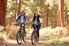 African American Couple Cycling Through Fall Woodland